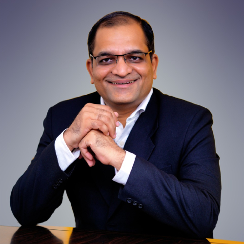 Man in suit with glasses, smiling.